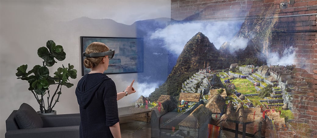 Woman wearing HoloLens looking at holographic scenery with ancient structures built on a misty mountainside